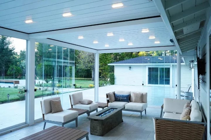 A patio adorned with elegant white furniture and enclosed by sliding glass doors