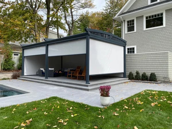 A backyard featuring a patio and a pergola, complemented by a motorized screen shade