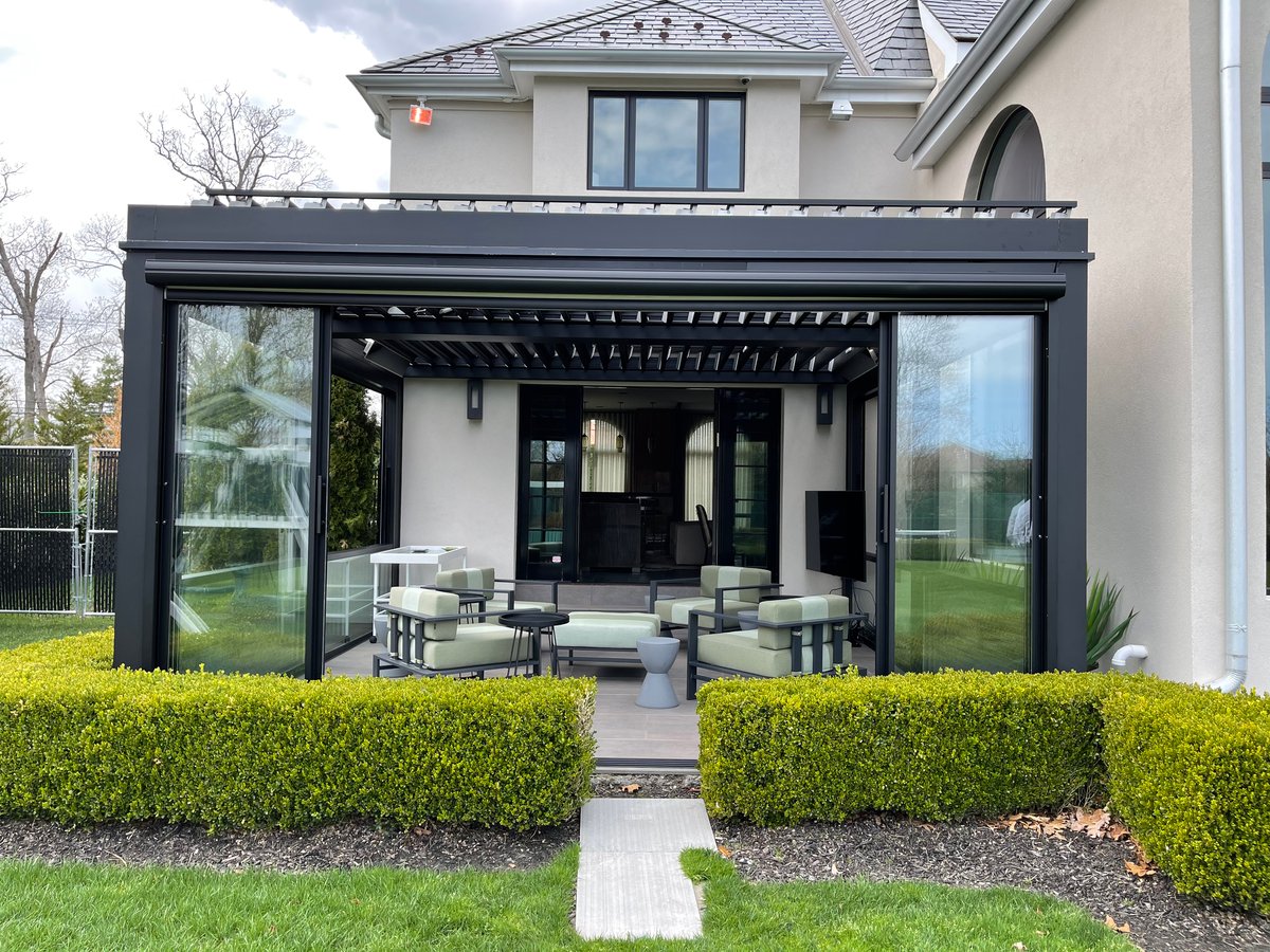  A chic patio with a black pergola and chairs, complete with a guillotine glass door