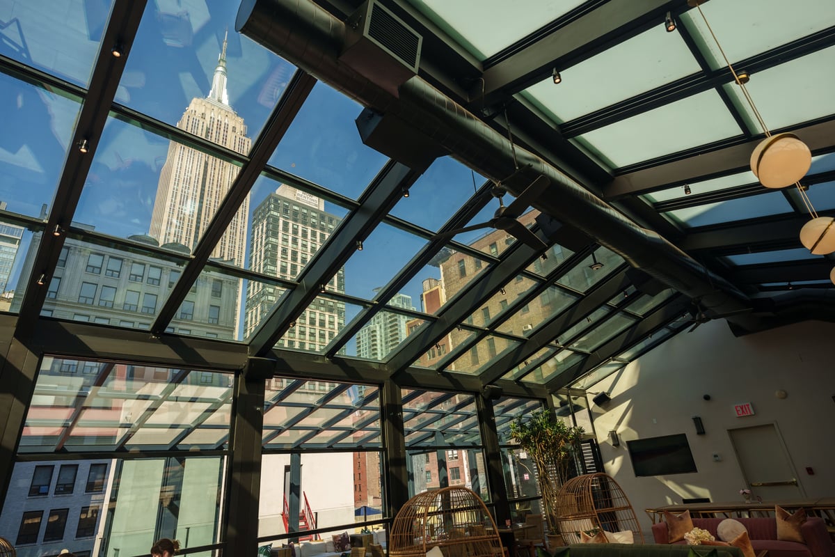 An elegant sunroom featuring expansive glass panels, inviting natural light to illuminate the cozy seating area