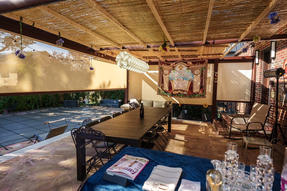 Retractable pergola sukkah with decorations, tables and chairs