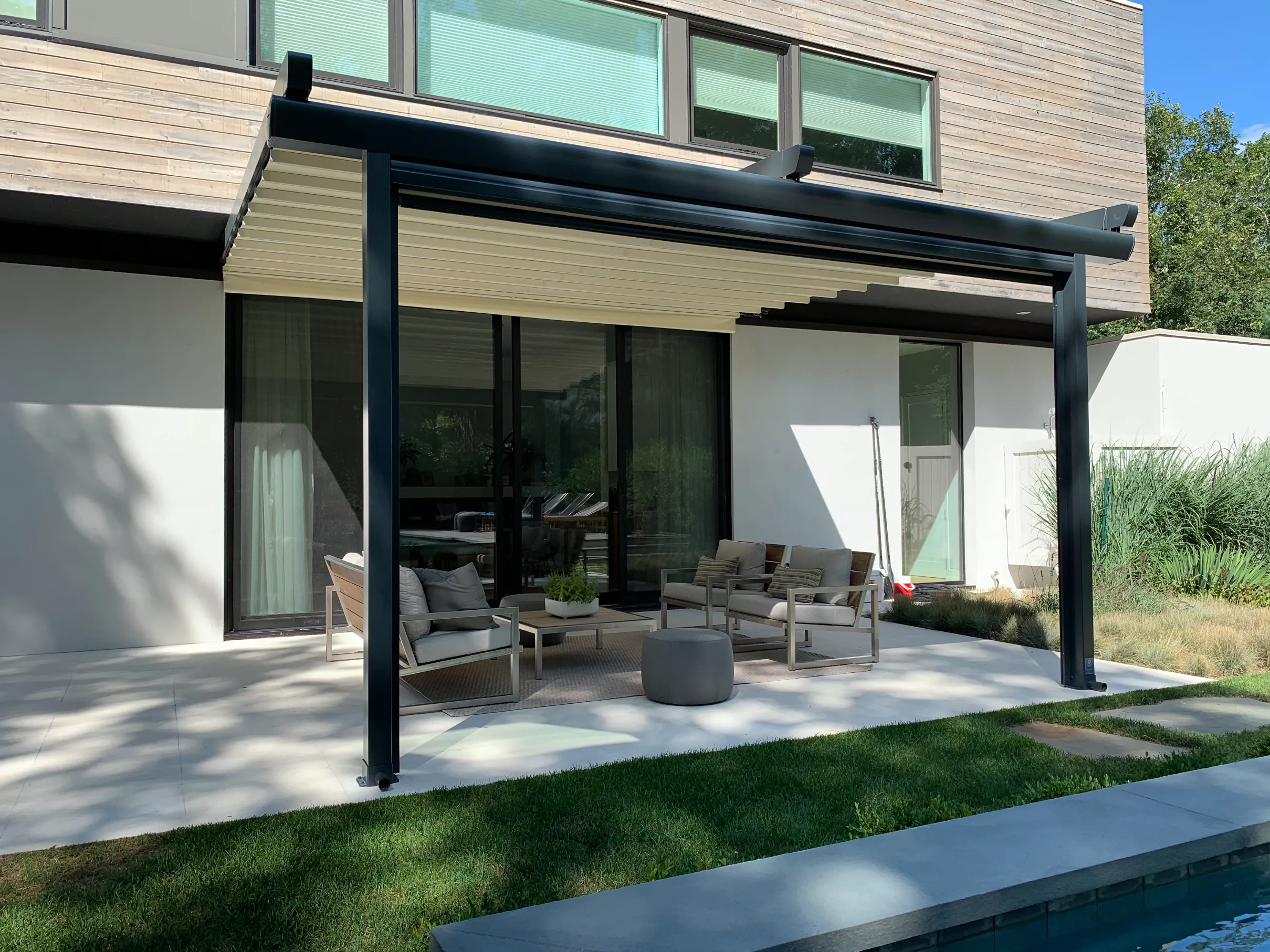 Featured image: Pergola with retractable canopy in a residential building with tables and chairs - Read full post: Stay Cool in the Summer: Benefits of a Pergola with a Retractable Canopy