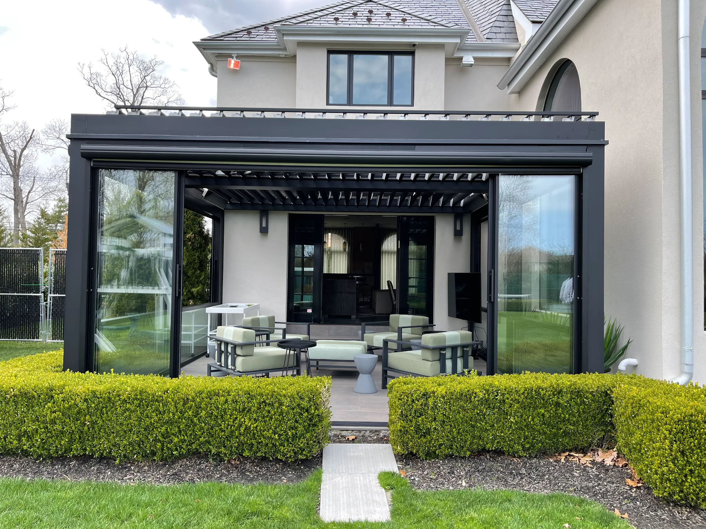 Featured image: A patio featuring a black pergola and chairs, surrounded by guillotine window walls - Read full post: Creating a Seamless Outdoor Experience with Guillotine Window Walls