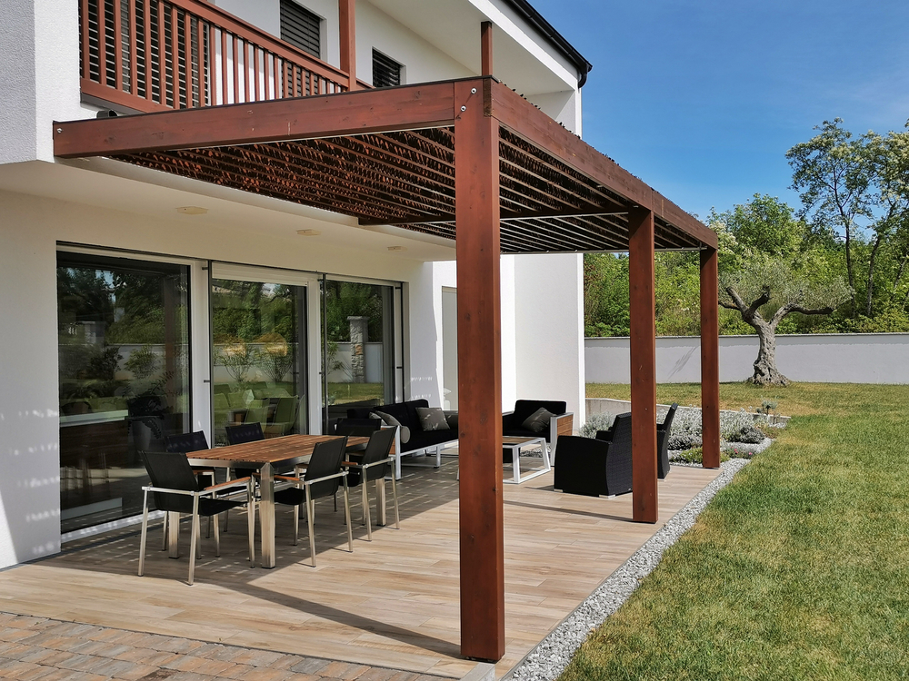Featured image: Pergola and terrace in the backyard of a modern house with tables and chairs - Read full post: 10 Ways to Customize Your Louvered Pergola to Fit Your Style